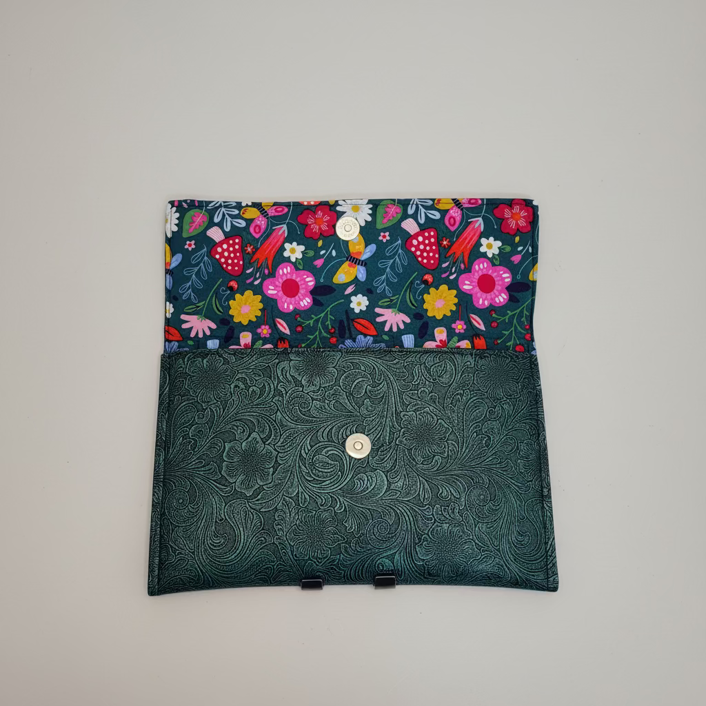 Floral-patterned fabric pouch with a green textured flap on a light background
