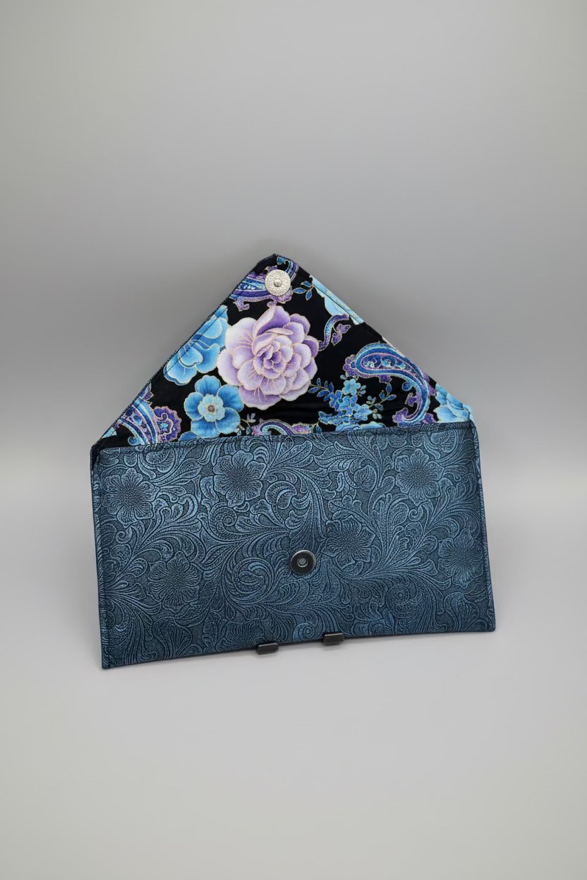 Floral-patterned fabric inside a blue embossed vegan leather clutch on a beige surface