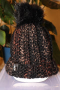 Brown, tan, and orange crocheted beanie with blackish brown faux fur pom pom