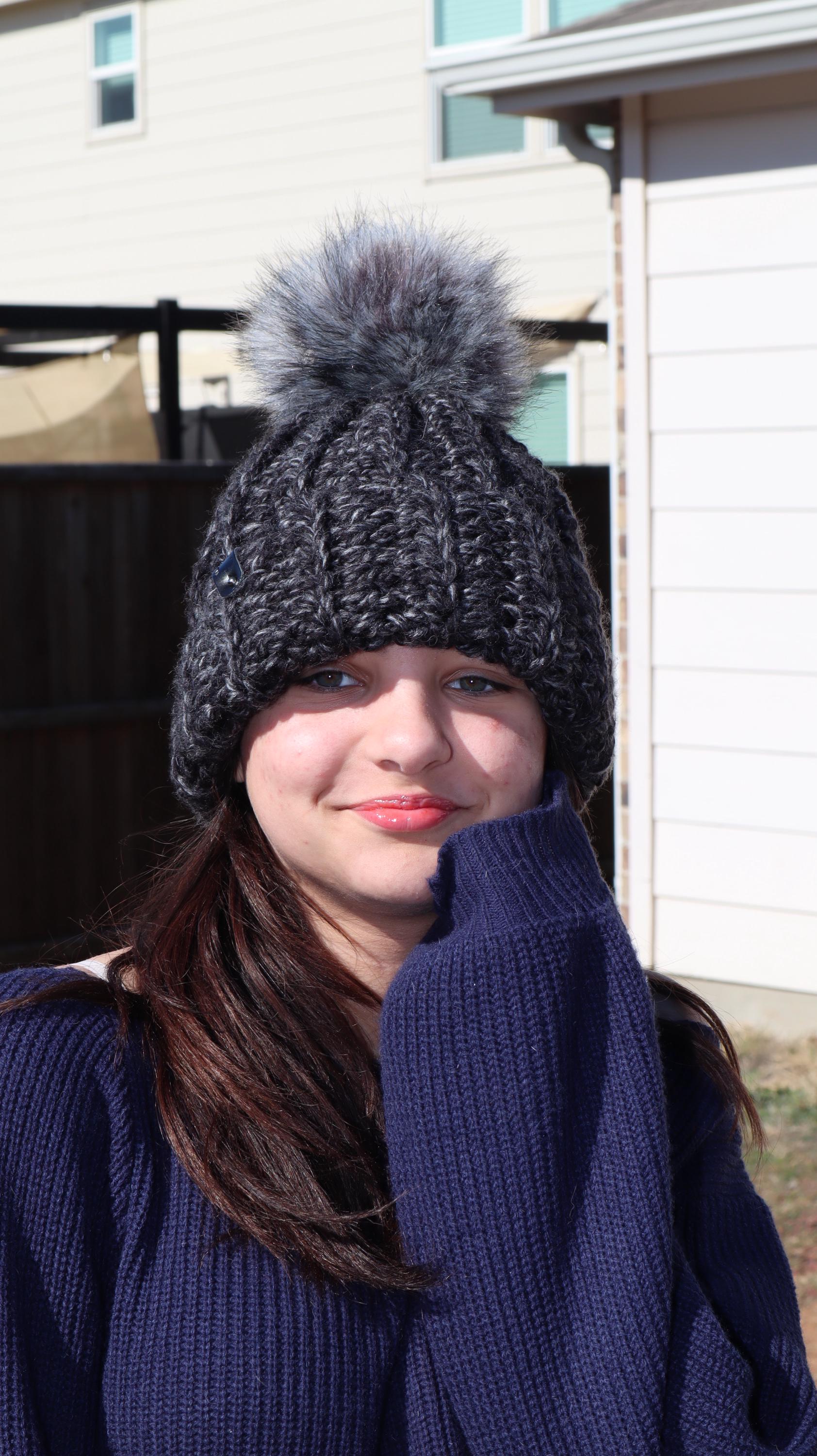 Model wearing black and gray crocheted knit beanie with gray faux fur pom-pom
